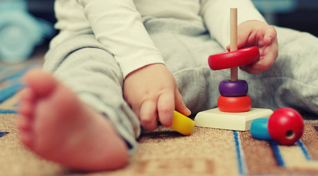 Infant exploring wooden toys at Sundrops Montessori